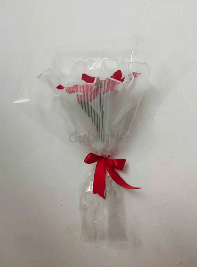 A beautifully handcrafted flower made from satin ribbon, wrapped in a transparent wrapping sheet.
