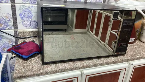 a Samsung microwave oven with a grill function, featuring a full glass door and a black finish.