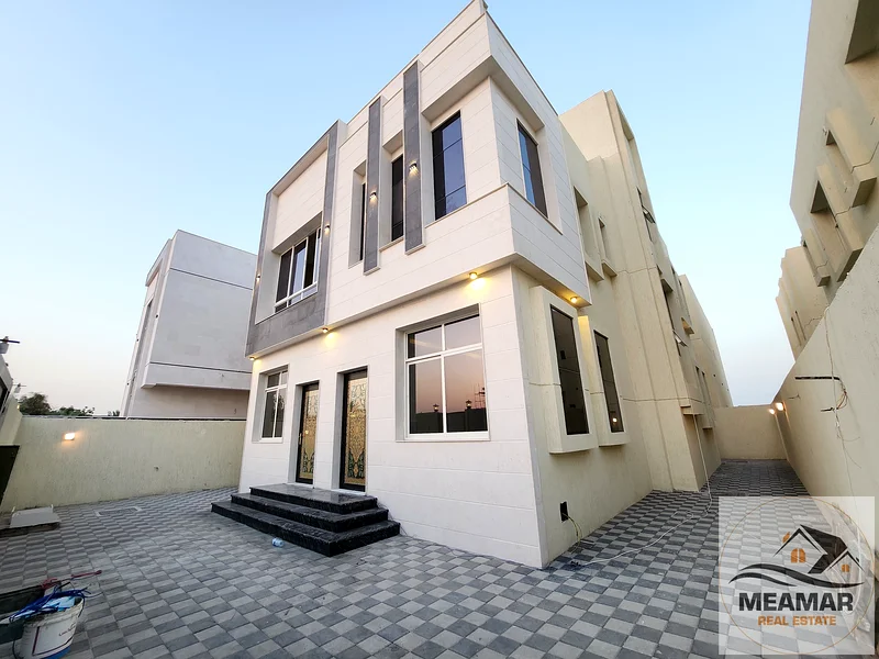 For sale, a luxurious villa in Al Helio, Ajman, 5 master bedrooms, a living room, and a hall, located in a strategic location near Mohammed bin Zayed63906384341890111