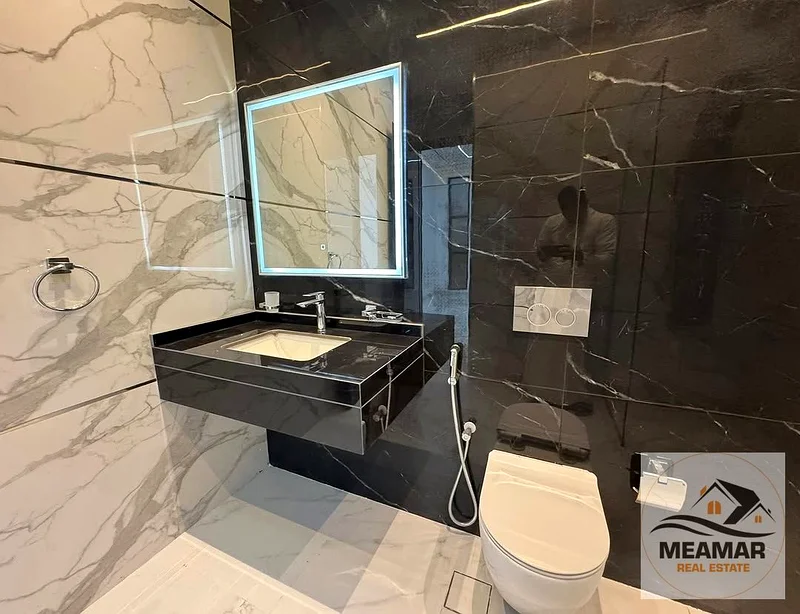 A luxurious, modern villa in Al Helio 1, featuring a stunning view and a spacious built-up area. The villa consists of two floors, ground and first, w63892471909634114