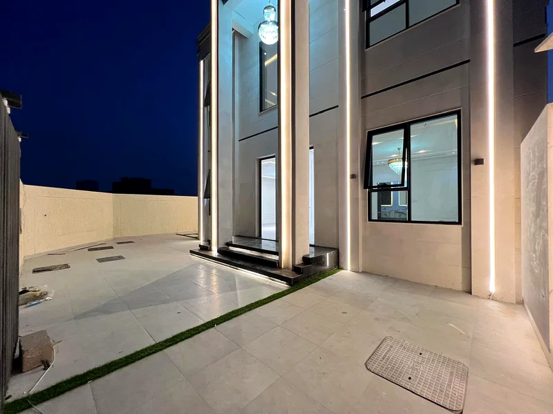 Corner villa for sale in Ajman, Al Helio 2 area, including registration fees, consisting of 4 master bedrooms, a majlis, a hall, and a large setback o63909006056705113