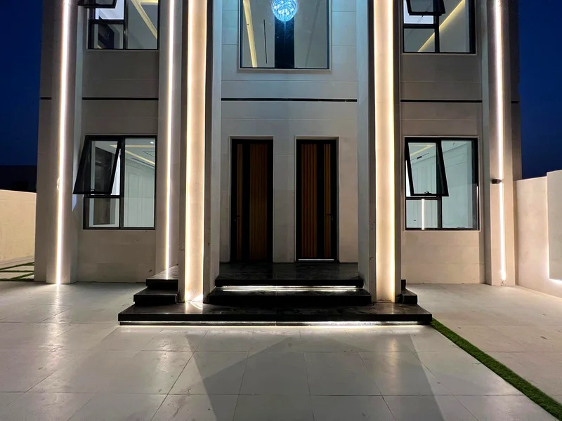 Corner villa for sale in Ajman, Al Helio 2 area, including registration fees, consisting of 4 master bedrooms, a majlis, a hall, and a large setback o63909006056705112