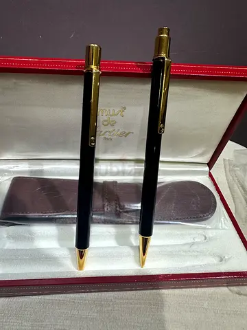 Two new Cartier pens stored in a Cartier leather case: a ballpoint pen and a pencil.