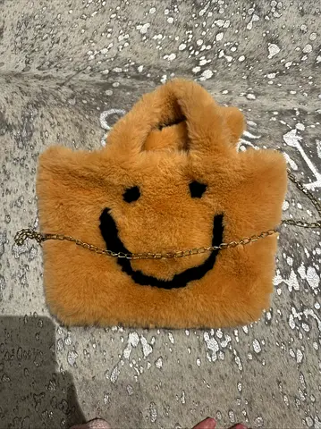An orange fluffy bag with a smiley face on it
