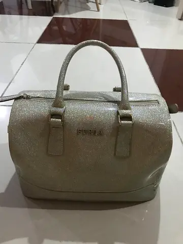 A collection of various womens bags, including a large gray tote bag, a short black bag, a gray Fur