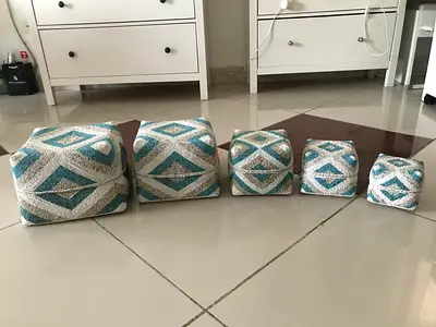 A set of 5 decorative wicker boxes with beads in a turquoise and beige color scheme. Originally from