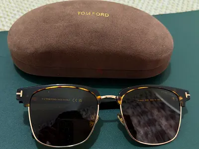 Tom Ford FT1139-K 01A sunglasses in shiny black with gold metal details and smoke lenses.