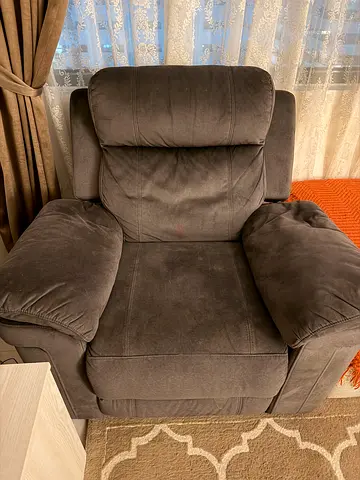 Comfortable Dark Grey Recliner Chair with a very soft material with a reclining back and leg rest.