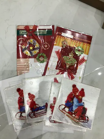 A set of New Years cards and a gift bag. The cards are decorated with glitter and bows. The cards f
