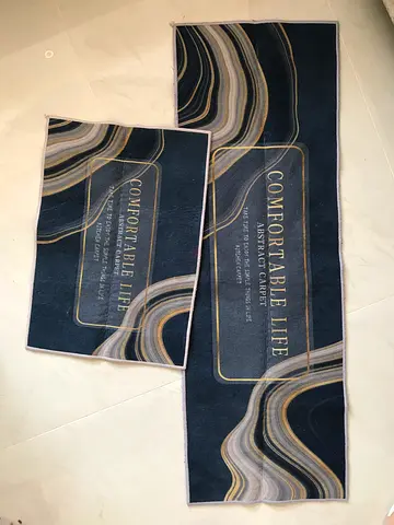 A set of kitchen rugs featuring an abstract marble-effect design in dark blue and gold tones. These