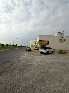 For sale: a corner commercial land in front of Al Houshi, Al Badia suburb, Sharjah. Area: 6006 sq ft