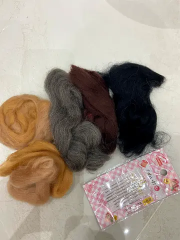 A craft kit containing materials for handicrafts. Felting wool: Strands of wool in various colors (b