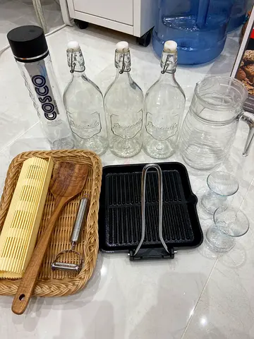 A variety of kitchenware, including cookware, water containers, and accessories. Cookware: Cast iron
