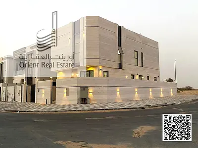 Corner villa for sale in Ajman, Al Helio 2 area, including registration fees, consisting of 5 master bedrooms, a living room, and a hall with a large