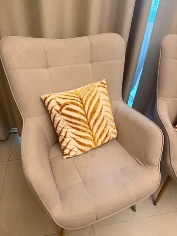 Pair of beige modern upholstered lounge chairs with gold legs