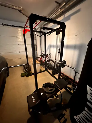My home power rack with lat pulldown, bench and weight plates and boxing bag