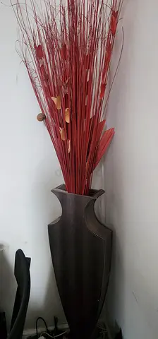 Tall black decorative floor vase with red dried stems