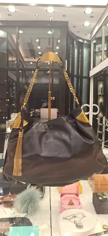 Black leather shoulder bag with gold chain straps and tassel