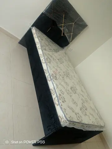 Single bed frame with mattress and black upholstered headboard