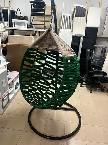 A birds nest design swing chair made from handwoven materials with comfortable cushions.