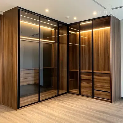 L-shaped built-in wardrobe with glass sliding doors and LED lighting