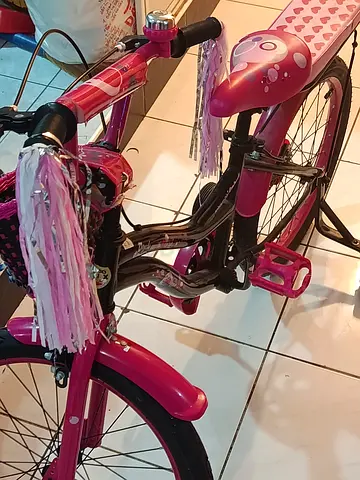 Pink childrens bike with front basket and handlebar tassels