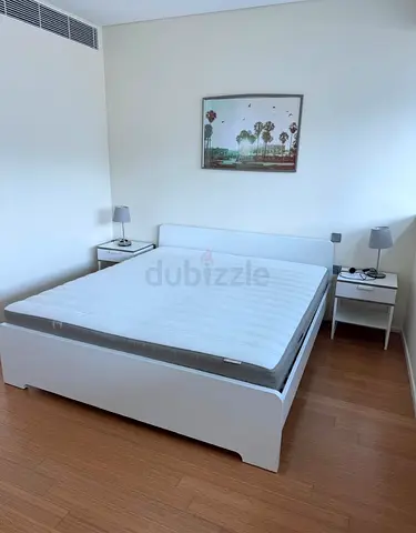 White bed frame with mattress and two bedside tables