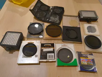 Assorted camera filters (UV, CPL, ND) plus small LED panel lights — used