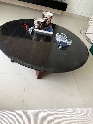 Round black marble coffee table with wooden legs .