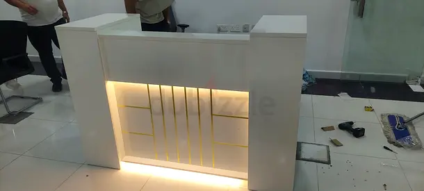 White reception desk with built-in LED lighting and gold trim