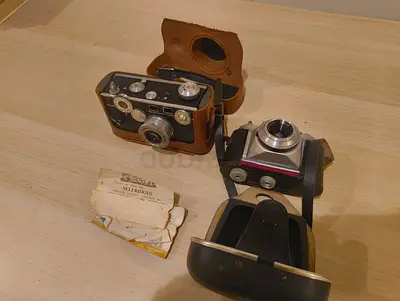 Pair of vintage 35mm compact film cameras with leather cases