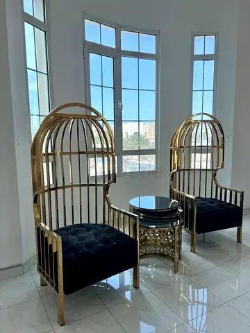 Pair of gold cage-style high-back chairs with matching side table