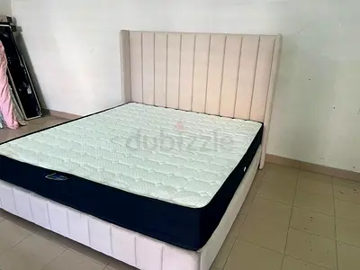 Modern bedroom with a high, padded headboard in a longitudinal design, and a mattress.