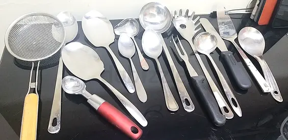 Assorted kitchen utensils — stainless steel ladles, spoons and serving tools