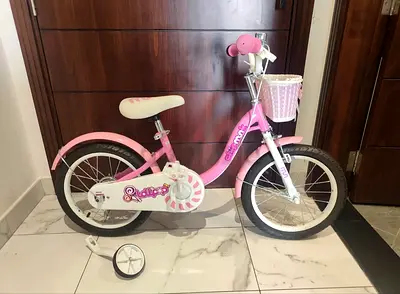 Pink childrens bike with training wheels and front basket