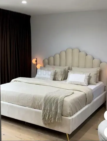 Beige upholstered bed with scalloped headboard -