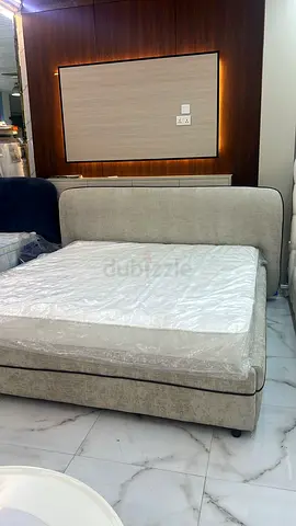 Light grey upholstered bed with mattress