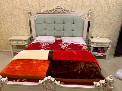 Ornate carved bed frame with tufted upholstered headboard and 2 matching nightstands
