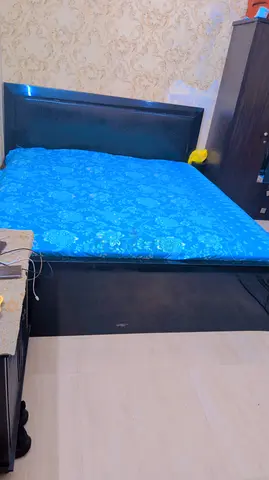 Black upholstered bed frame with headboard and spring mattress