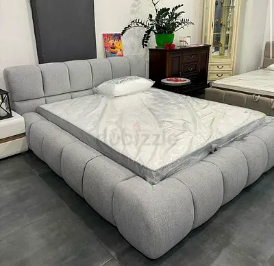 Grey upholstered platform bed frame with rounded tufted design