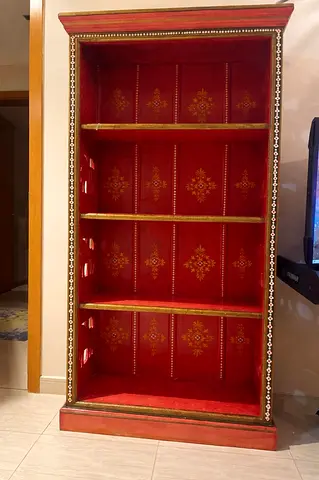 Red vintage-style wooden bookcase with decorative gold stencil