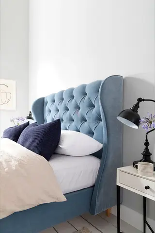 My blue upholstered bed with tufted wingback headboard