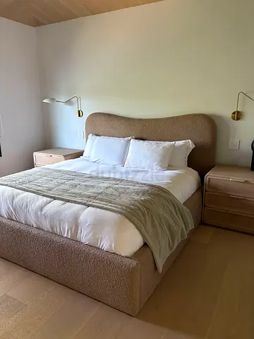 Upholstered king bed with curved headboard in neutral beige