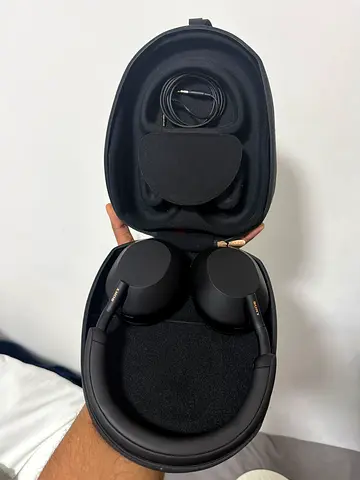 Over-ear wireless noise-cancelling headphones with case and cable.