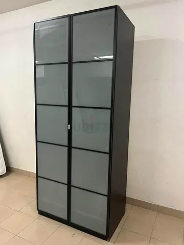 An IKEA PAX wardrobe featuring a black frame and frosted glass doors.