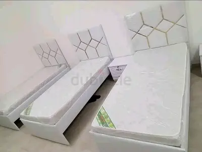 Pair of white single beds with mattresses and matching headboards