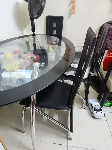 Round glass dining table with 3 black chairs