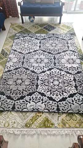 Two layered area rugs — gray damask rug on green patterned rug