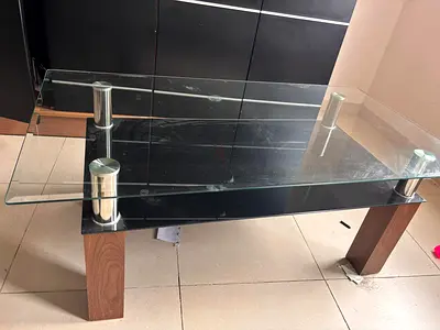 Glass coffee table with wood legs and black lower shelf