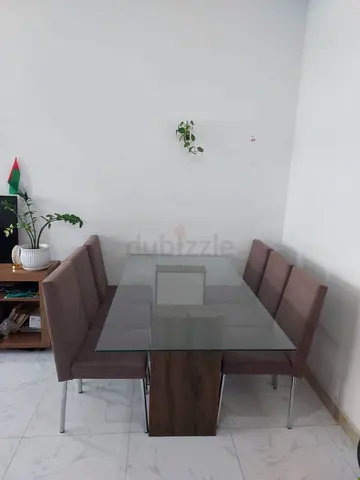 Glass-top dining table with 6 brown upholstered chairs